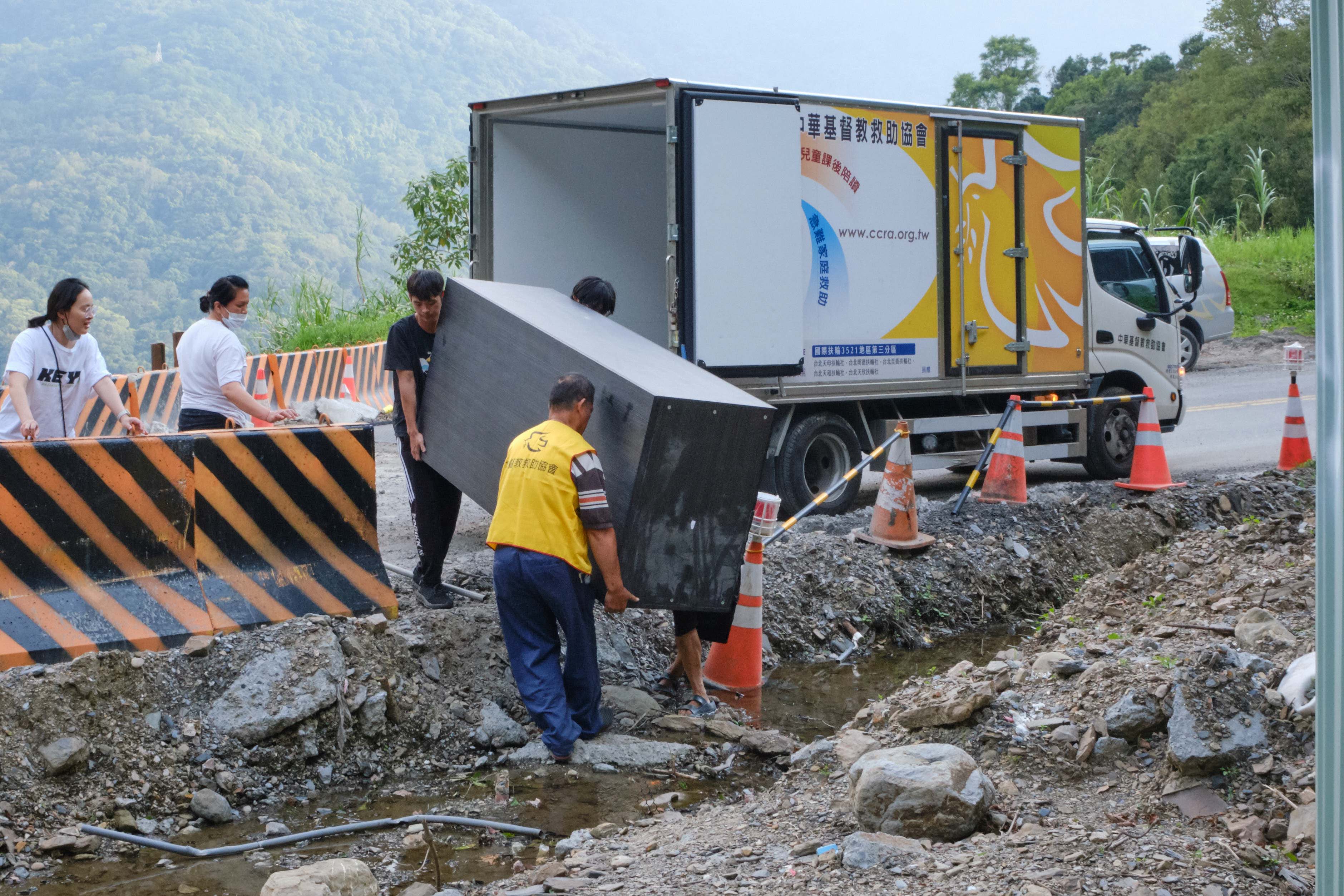 前往受災戶的道路仍在修復，救助協會志工徒手搬運大型家具至助受災戶重整家園。